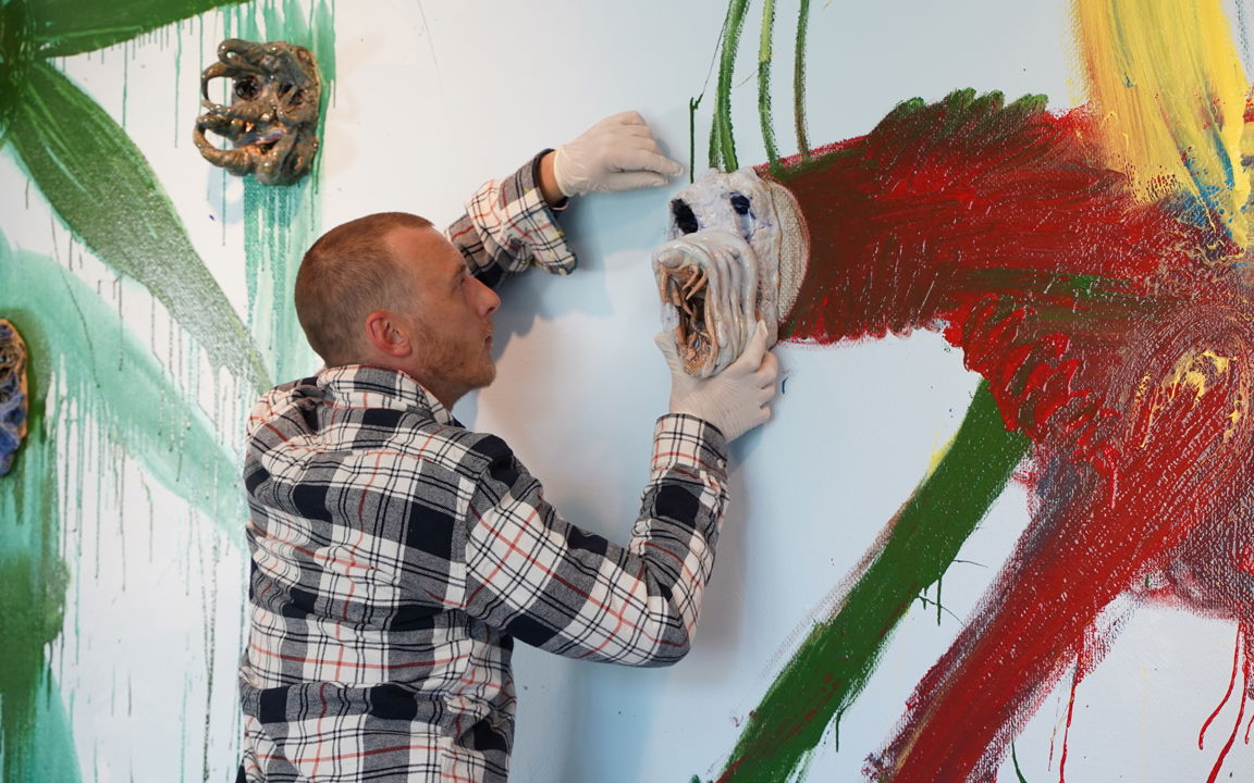 Næblerød monterer maske på vægmaleri